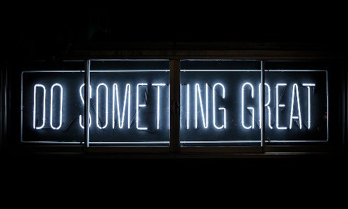 Neon sign with white letters that read "Do Something Great"