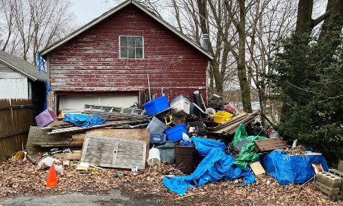 Pile of junk in front of a red house.