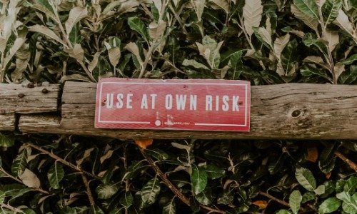 Red sign on a wood railing that reads "Use at your own risk"