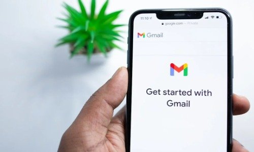 Hand holding phone with Gmail logo and "Get Started with Gmail" in black text on white screen