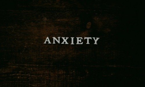 The word Anxiety in white letters on a black textured background